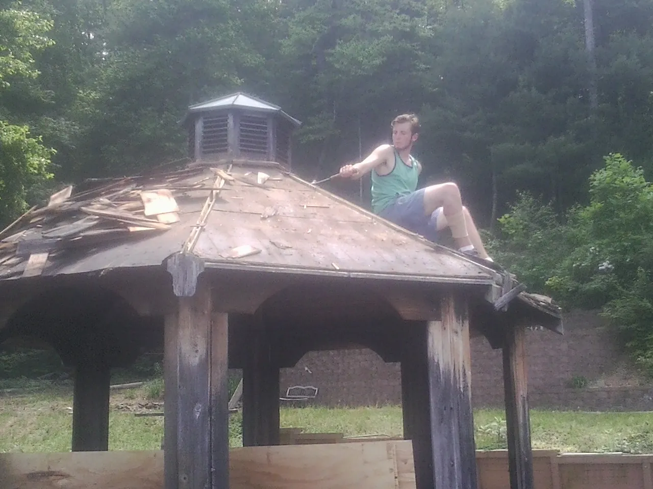 Tearing the old roof off a wooden gazebo before new shakes in Magna