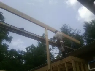 Carpenter setting a ridge beam over a new addition frame — Ice Dam Removal by Roofing Brothers in Magna
