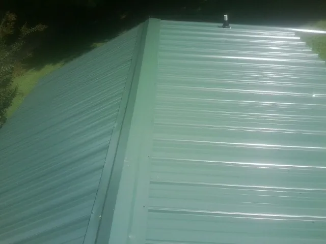 New green metal panels meeting at the ridge of a roof — Flat Roof Repair work by our crew in Magna