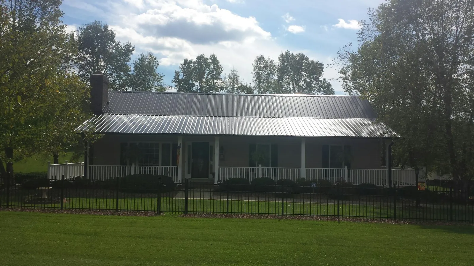 Gray metal roof on a brick ranch with a full width front porch — Gutter Guard Installation work by our crew in Magna