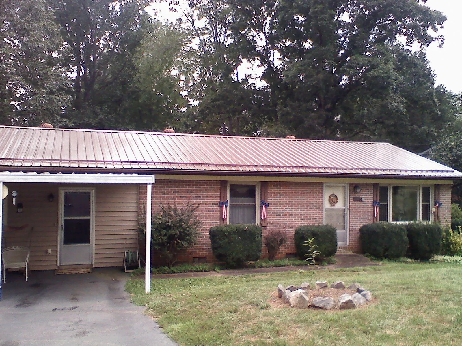 Bronze metal roof and carport on a brick ranch home — Roof Repair work by our crew in Magna