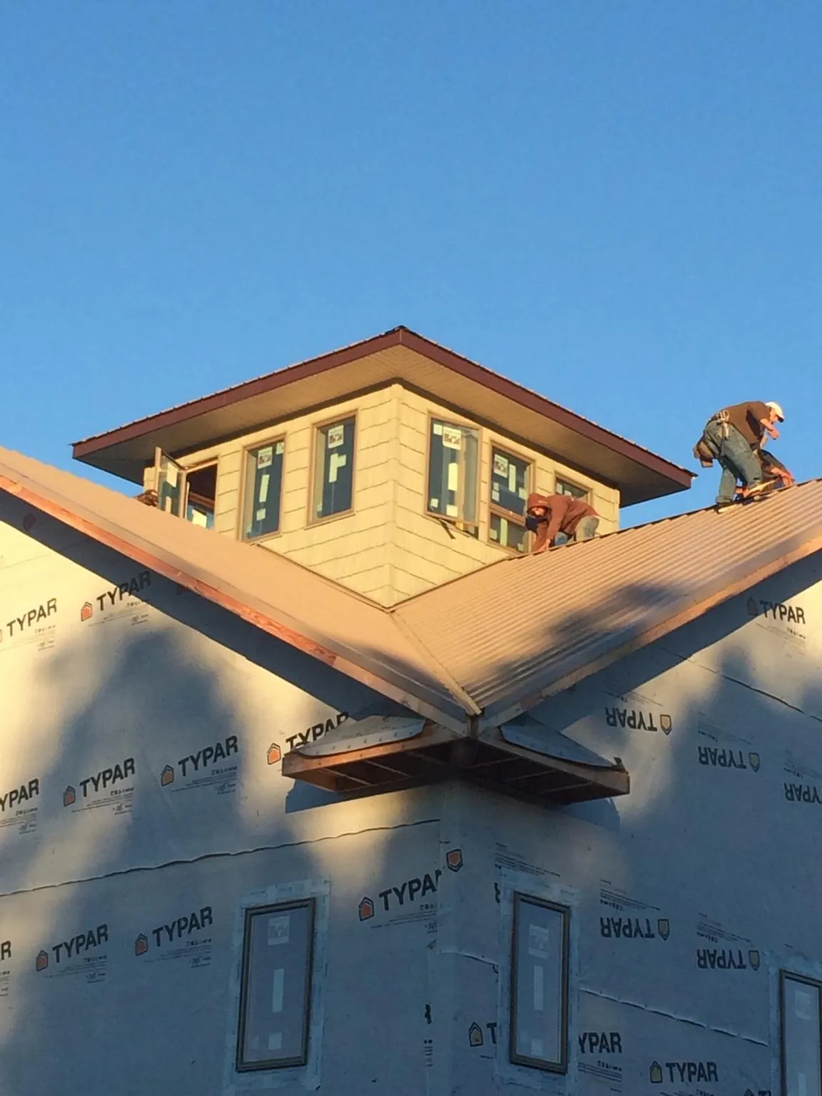 Roofers working around a rooftop cupola on a new metal roof at sunset — Roof Waterproofing in Magna by Roofing Brothers